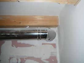 Obrázek 2 – Vedení vícevrstvého, kovového kouřovodu pod vodorovným dřevěným trámem stropu v menší vzdálenosti od jeho povrchu než povoluje výrobce systémového kovového komína, ze kterého je kouřovod sestavený.